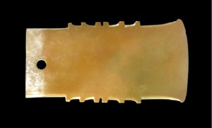 玉戚 商代 长10.7、宽5.2厘米 现藏于首都博物馆 玉质经侵蚀为姜黄色，上部呈灰质白色。体扁薄精巧，呈梯形，肩平窄，两面磨刃。玉钺腰两侧琢磨出外凸的六个齿牙，间距不等，左右对称。内上端有一个单面钻圆孔。