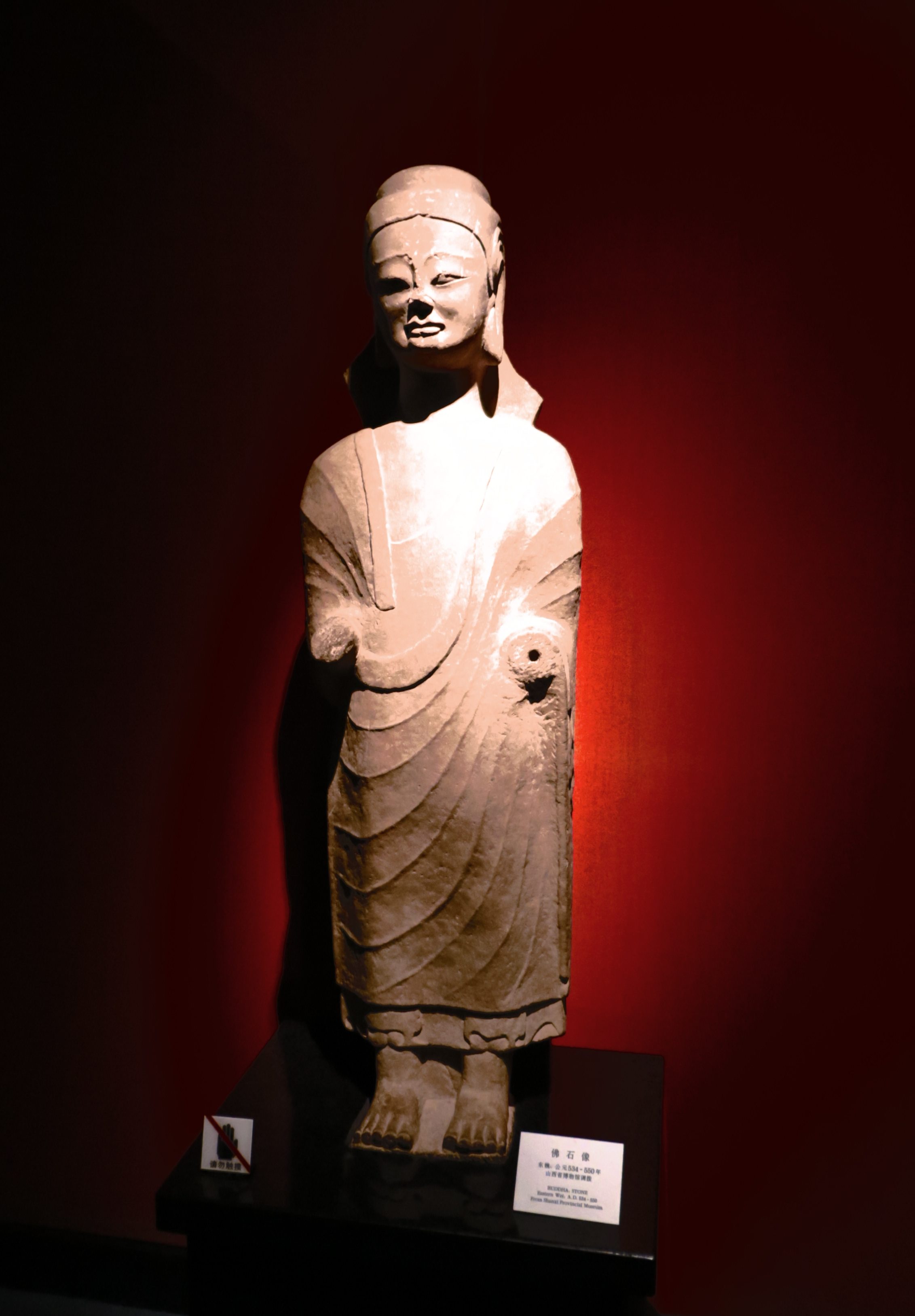 佛石像，东魏（534-550），山西博物馆调拨。佛像表情庄严安详，身披袈裟，轻薄而贴体。疏朗而平行的褶皱恰如其分地表现出衣物的柔和，并使造像在静谧中带上了隐约的动感