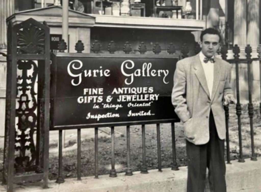 ALEX GUREVICH (1929-1990), PHOTOGRAPHED IN FRONT OF GURIE GALLERY, MONTREAL, CIRCA 1954. ALEX GUREVICH (1929-1990)，攝於 GURIE GALLERY 門前，蒙特利爾，約1954年